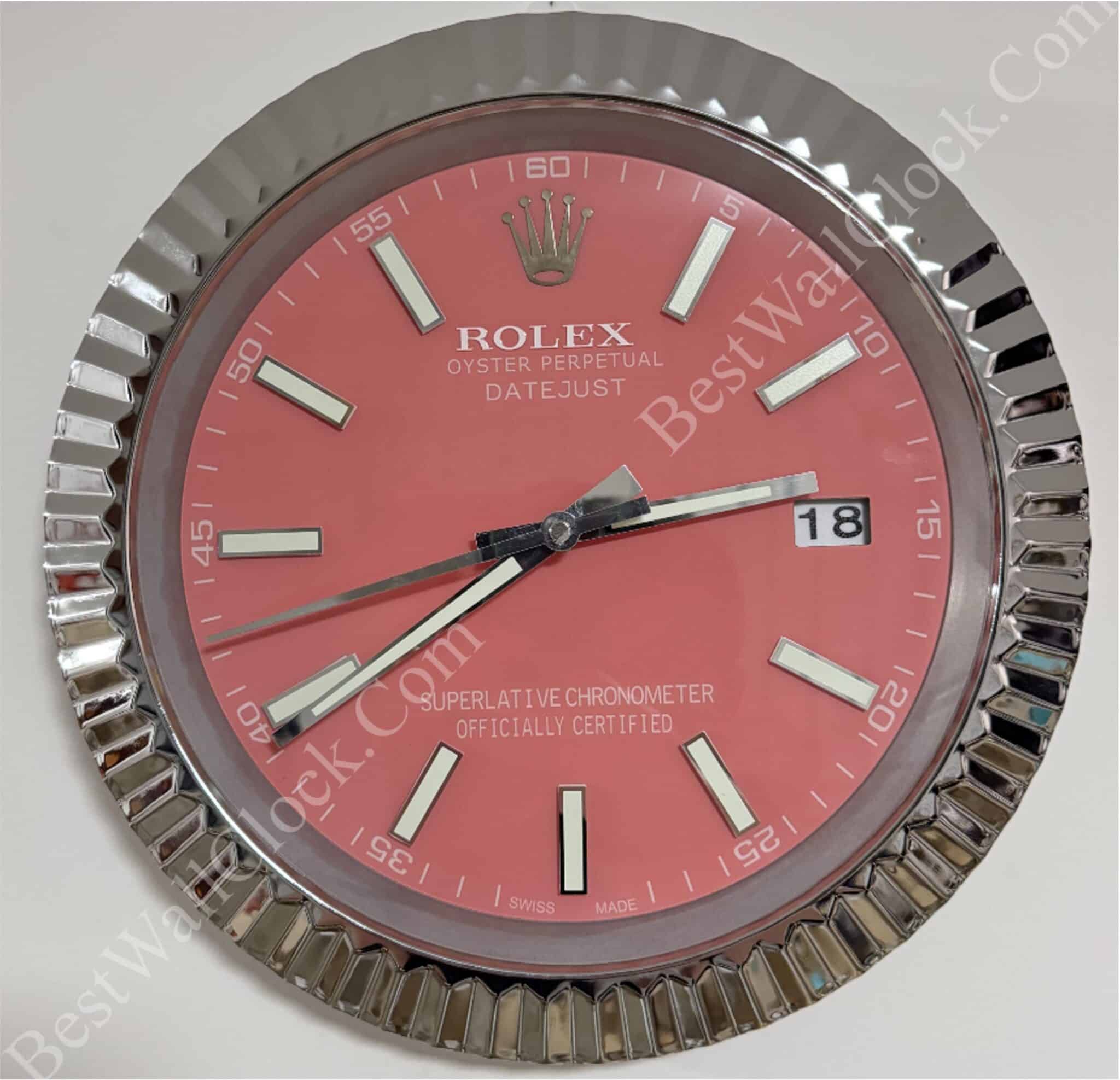 Close-up of a round Rolex Oyster Perpetual Datejust watch face with a pink dial, silver hour markers, silver hands, a date window showing 18, and a ridged silver bezel.