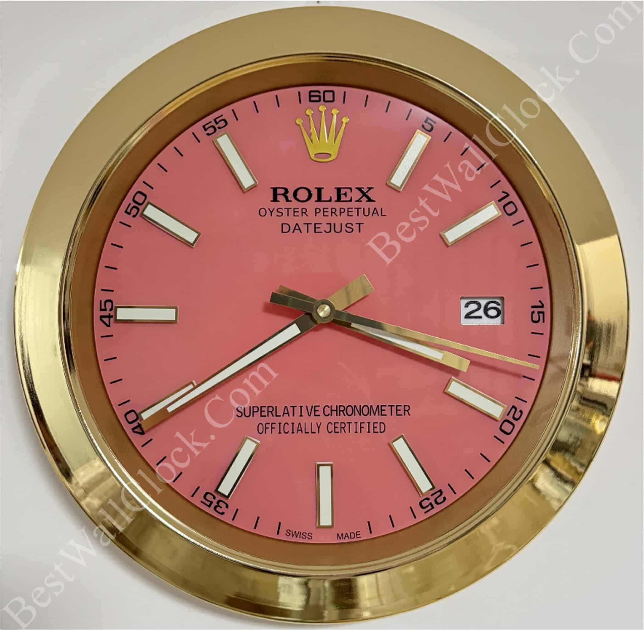Wall clock styled as a Rolex Oyster Perpetual Datejust watch with a pink face, gold rim, white hour markers, and date display showing 26, with the time showing 7:39:15.