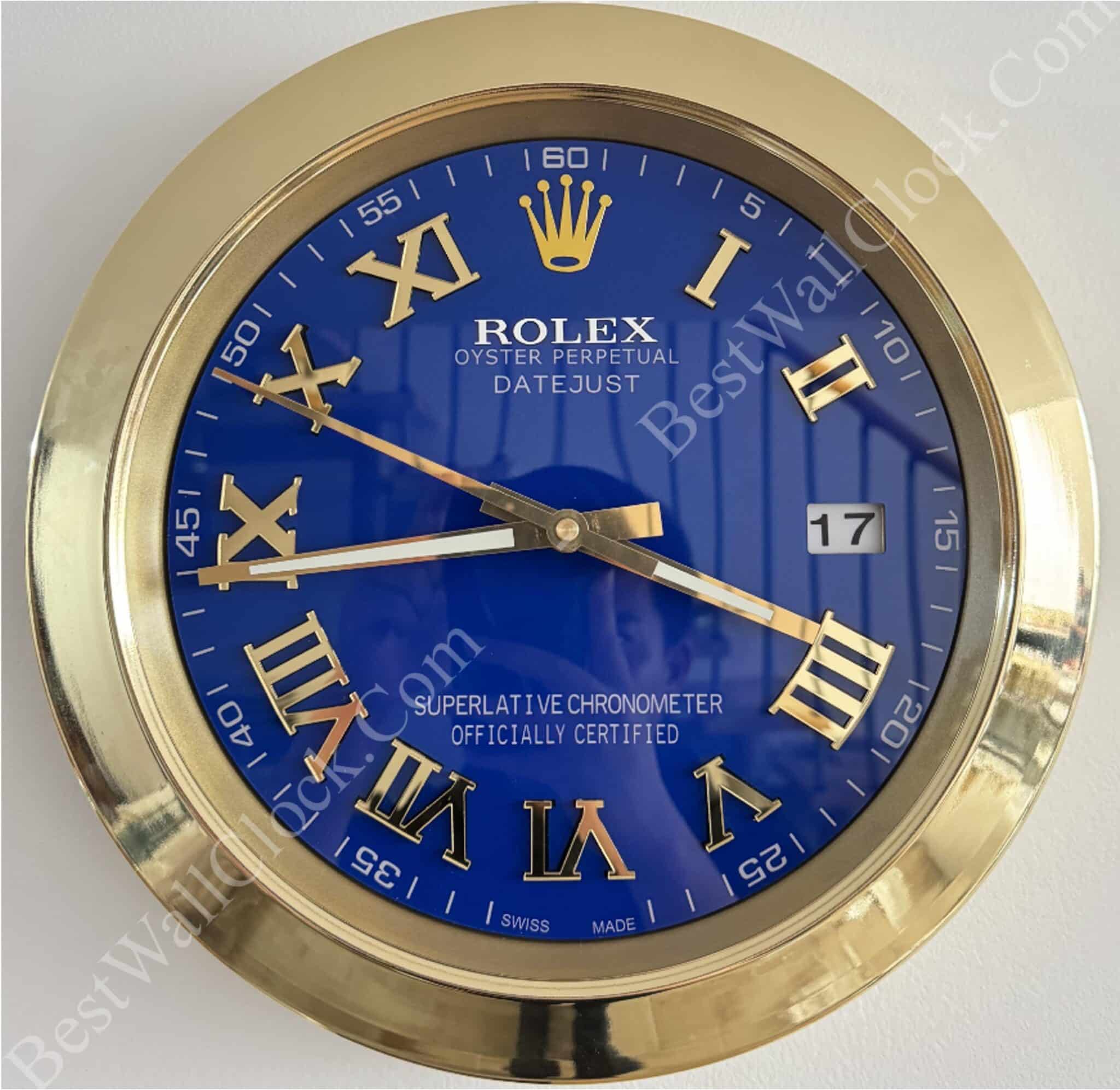 Wall clock designed like a Rolex Oyster Perpetual Datejust watch with a blue dial, gold Roman numerals, and gold frame, showing the date as 17 and the time as approximately 8:48.