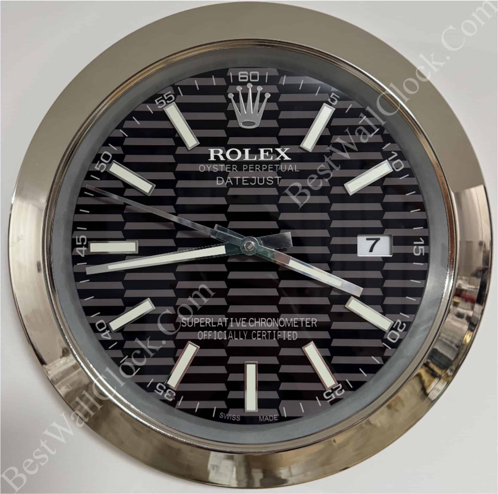 Rolex well clock featuring a black patterned dial with silver hour markers and hands inside a shiny metallic round frame, showing the date at 3 o'clock