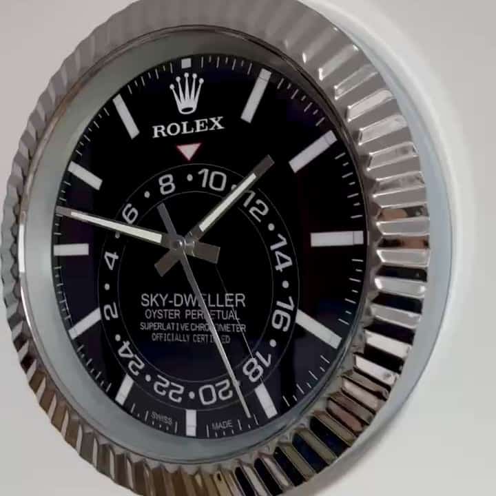 Close-up of a Rolex Sky-Dweller Oyster Perpetual watch face with black dial, white hour markers, and silver hands inside a fluted silver bezel.