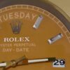 Close-up of a gold Rolex watch face showing the day tirsdag, diamond hour markers, and date 29 with gold and white hands.