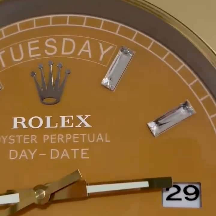 Close-up of a gold Rolex watch face showing the day tirsdag, diamond hour markers, and date 29 with gold and white hands.