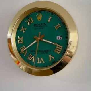 Rolex wall clock with a gold frame, green face, and gold Roman numerals showing the time as 3:39 with a date window displaying 17