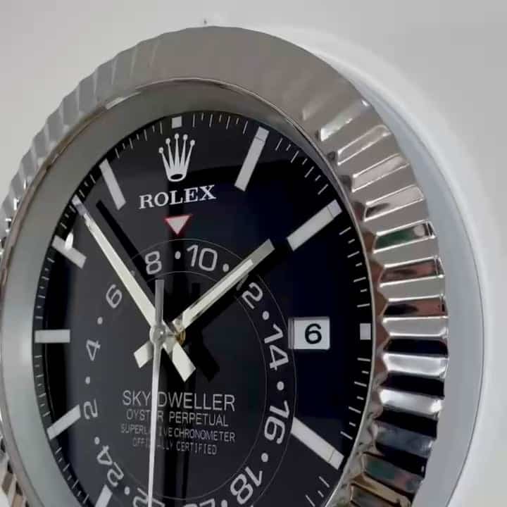 Close-up of a Rolex Sky-Dweller wristwatch with a black dial, silver hour markers, and a date window showing the 6th, encased in a fluted silver bezel.