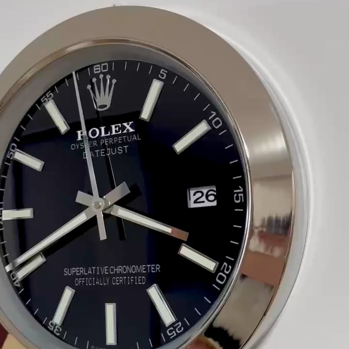 Close-up of a Rolex Oyster Perpetual Datejust watch face with a black dial, white hour markers, and a date display showing the 26th, surrounded by a silver bezel.