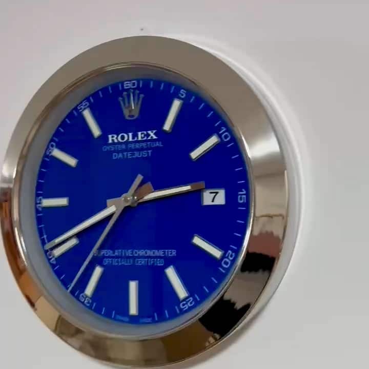 Round wall clock designed to resemble a Rolex Oyster Perpetual Datejust watch with a blue face, white markings, and silver hands showing the time as 2:38.