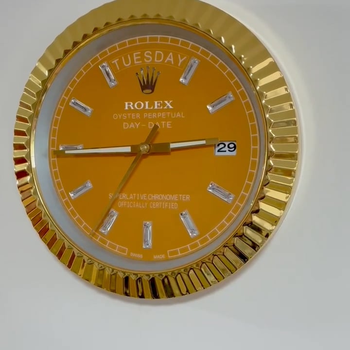 Close-up of a gold Rolex Oyster Perpetual Day-Date watch face showing the day as Tuesday and the date as the 29th, with a gold bezel and diamond hour markers.