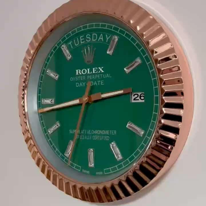 Close-up of a Rolex Oyster Perpetual Day-Date watch with a green dial, rose gold fluted bezel, diamond hour markers, displaying Tuesday and the 26th date, showing time at approximately 2:44:35.