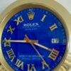 Close-up of a Rolex Oyster Perpetual Datejust watch with a blue dial, gold Roman numeral hour markers, gold hands showing the time as 9:45:24, and a date window displaying the number 17.