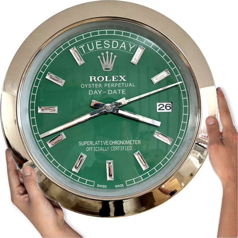 Green Rolex wall clock with a gold frame showing the day as terça-feira and the date as 26, held by two hands on a white background.
