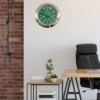 Modern office corner with a black leather chair, wooden desk, small side table with books and potted plants, brick accent wall on the left, and a green Rolex wall clock showing terça-feira 3:15 with the date 26 on a plain white wall