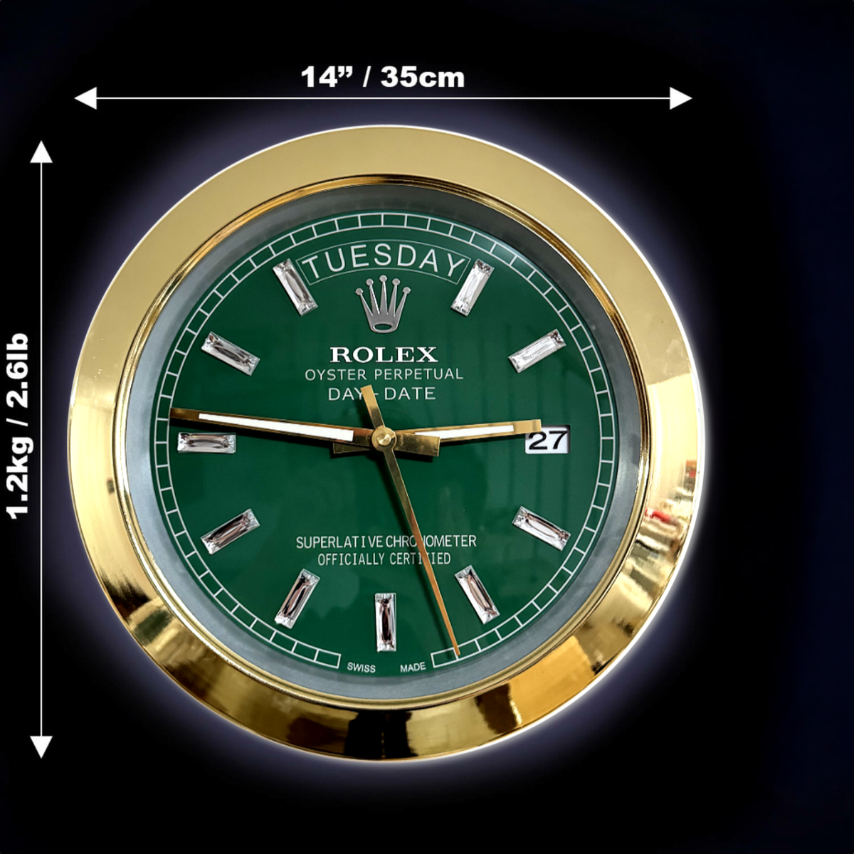 Close-up of a Rolex Oyster Perpetual Day-Date watch face with a green dial, gold bezel, day displayed as Dinsdag, and date as 27, with dimensions 14 inches / 35 cm diameter and weight 1.2 kg / 2.6 lb annotated around it.