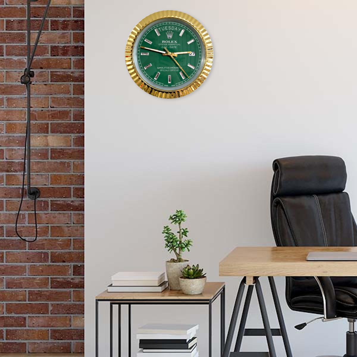 Modern office space with a black leather chair, wooden desk, small side table with stacked books and potted plants, brick wall on the left, and a green and gold Rolex wall clock showing Dinsdag 27 on a white wall.