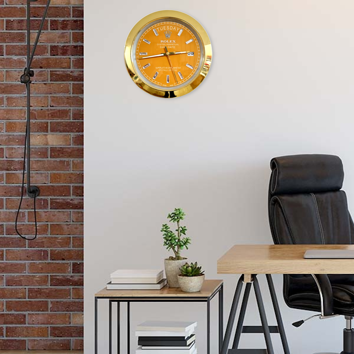 Modern office interior with a wooden desk, black ergonomic chair, small side table holding potted plants and stacks of books, against a white wall and a brick accent wall. A large gold-framed clock with an orange face and the Rolex logo is mounted on the white wall.