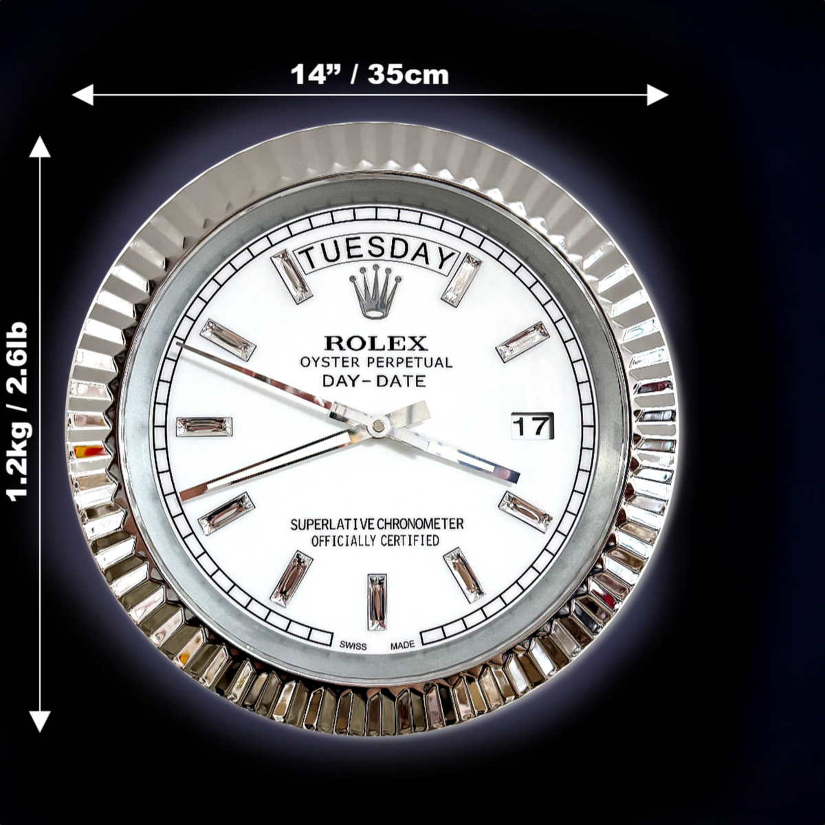 Close-up of a white Rolex Oyster Perpetual Day-Date clock face with day and date display, silver hour markers, and silver fluted bezel, with dimensions 14 inches (35 cm) in diameter and weight 1.2 kg (2.61 lb) indicated with arrows on a black background