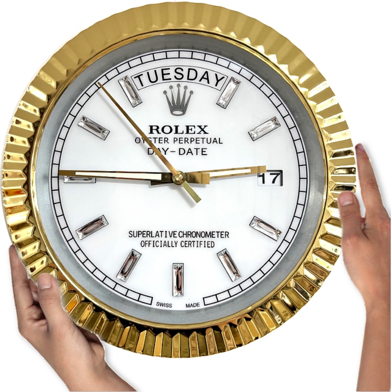 Hands holding a round Rolex wall clock with a gold fluted bezel, white dial, silver hour markers, displaying Salı and the date 17, with gold hour and minute hands and a gold second hand.