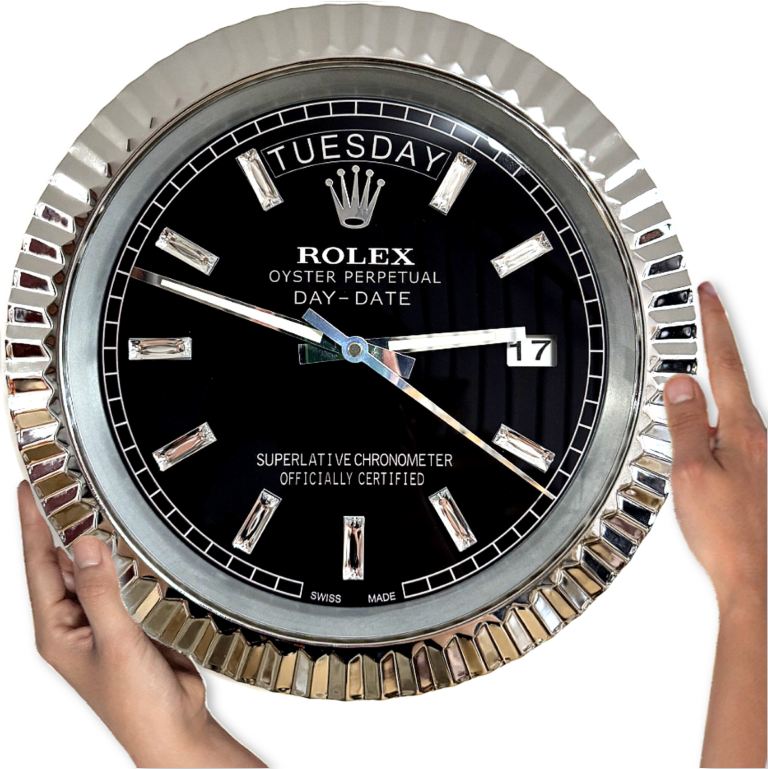Large round black Rolex wall clock with silver fluted bezel displaying Dinsdag and date 17, held by two hands on either side