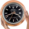 Hand holding a large round Rolex Oyster Perpetual Day-Date clock with a black face, rose gold ridged bezel, and diamond hour markers showing the day as terça-feira and the date as 17.