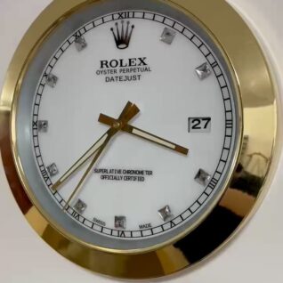 Close-up of a Rolex Oyster Perpetual Datejust wall clock with a white face, gold hands, diamond hour markers, and a gold rim, showing the time as 3:36 and the date as 27.