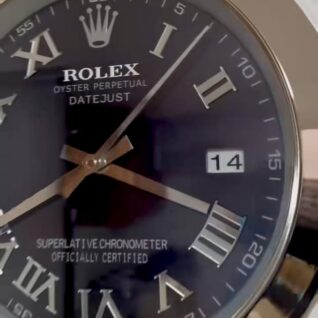 Close-up of a Rolex Oyster Perpetual Datejust watch face with black dial, gold Roman numerals, gold hands, and a date window showing the 14th.