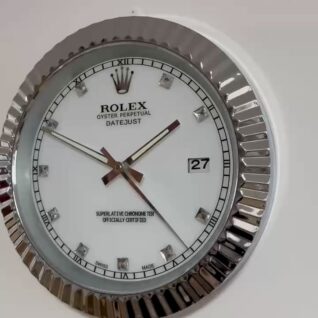 Close-up of a Rolex Oyster Perpetual Datejust wall clock with a fluted silver frame, white dial, diamond hour markers, Roman numerals at quarter hours, and a date display showing 27.