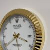 Close-up of a white Rolex Oyster Perpetual Datejust clock with gold hands, diamond hour markers, and a gold textured bezel, showing the date as 27.