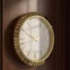 Round wall clock with a gold fluted frame, white face, gold hour markers, and black hour, minute, and second hands showing the time 02:20:18, branded with the Rolex logo and crown above the name on the clock face, placed on a tiled floor against a beige wall.
