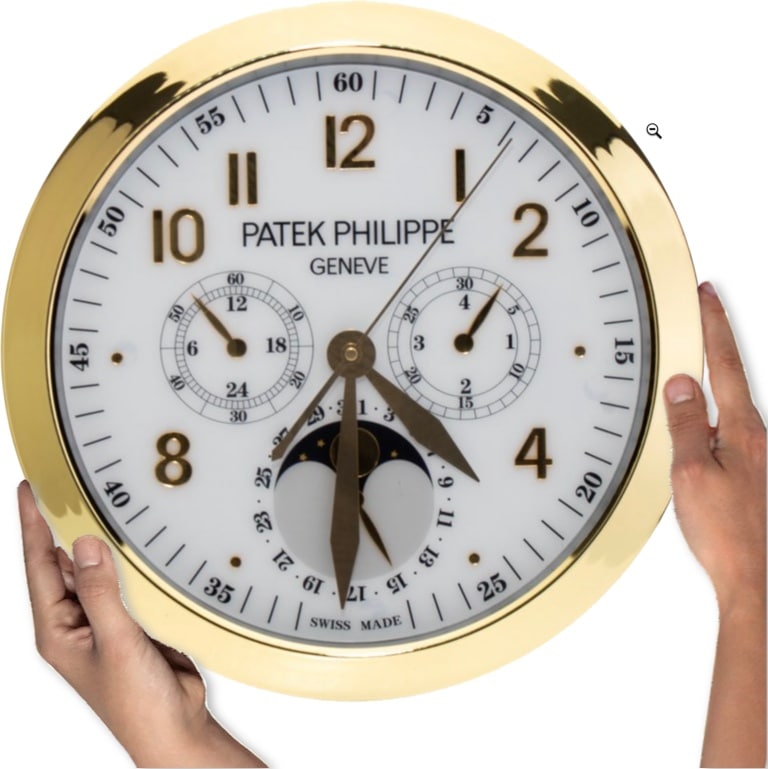 A person holding a large Patek Philippe Geneve wall clock with a gold rim, white face, and multiple subdials alongside date and moonphase indicators, described as a rolex wall clock in the text.